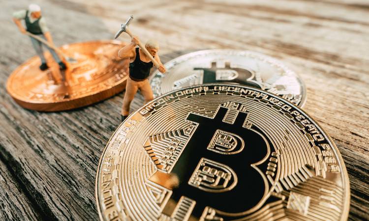 Bitcoin Mining miniature people diging on valuable coin wood background